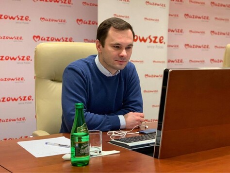 Przed monitorem siedzi dyrektor Wajda. Przed nim na stole widać dokumenty