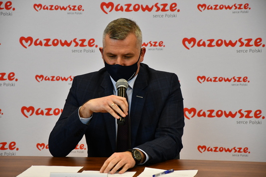 Wicemarszałek siedzi za stołem w maseczce na twarzy