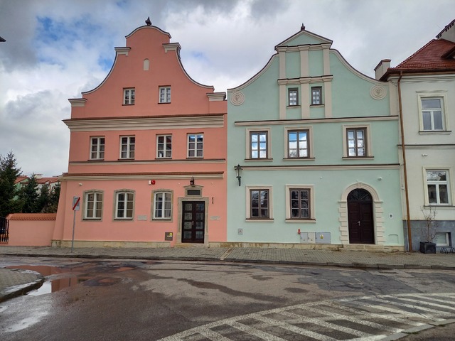 Dwie symetryczne, wyremontowane kamienice w kontrastujących kolorach, widok od frontu