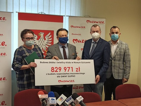 Marszałek, wicemarszałek i dyrektor płockiej delegatury oraz beneficjentka stoją obok siebie i pozują do zdjęcia. Marszałek i beneficjentka trzymają tablicę z kwotą dofinansowania na budowę żłobka