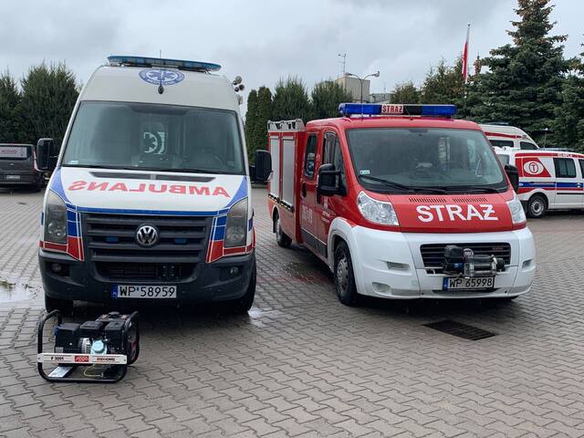 Na parkingu, obok siebie stoi wóz strażacki oraz ambulans