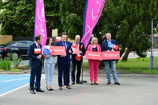 Grupa osób stoi z czerwonymi tabliczkami