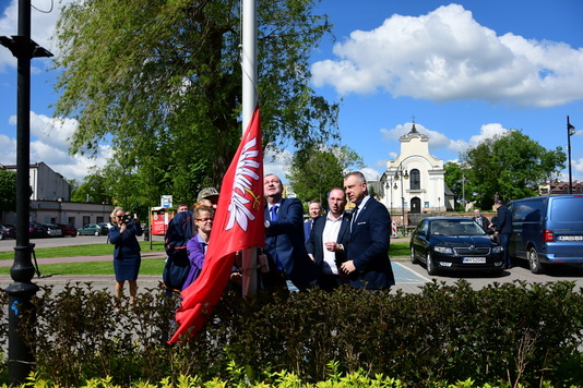 Grupa osób wciąga flagę na maszt