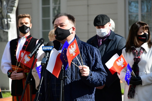 Maeszałęk w maseczce zasłaniającej usta i nos trzyma chorągiewkę 