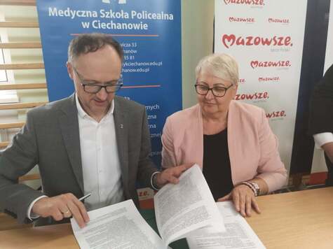 Mężczyzna podpisuje dokumenty, obok kobieta przegląda umowę