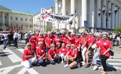 grupa strajkujących pielęgniarek przed Mazowieckim Urzędem Wojewódzkim w Warszawie z transparentem "Za ciężką pracę pieniądze nam się należą"