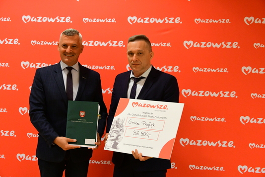 Dwóch mężczyzn z czekiem na tle ścianki z logo Mazowsza