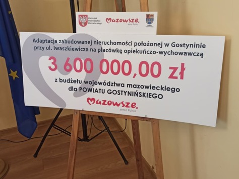 Na stojaku stoi duży czek z kwotą 3,6 miliona złotych.