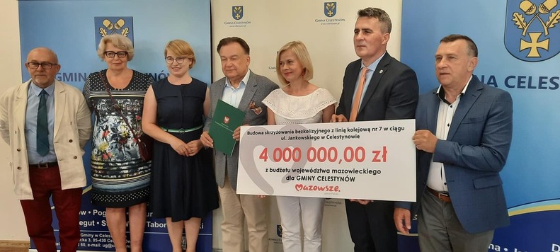 cała grupa pozujue do zdjęcia z czekiem i umową