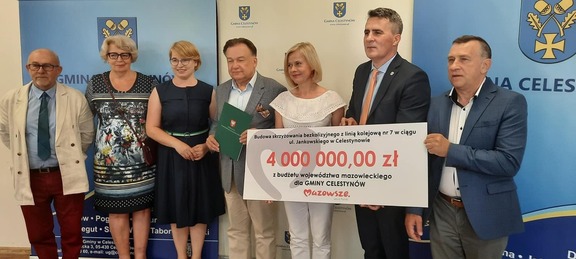 Grupa osób stoi z czekiem, dwie kobiety i dwóch mężczyzn