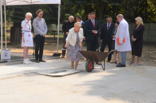 Kobieta w sukience i białej marynarce wmurowywuje akt erekcyjny