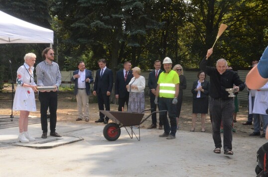 Na zdjeciu stoi 6 mężczyzn, trzy kobiety oraz taczka z betonem