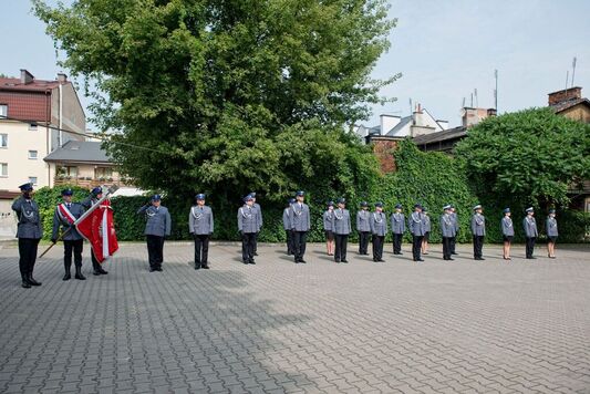 Policjanci ustawieni w dwóch rzędach stoją na placu