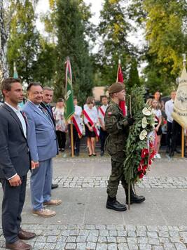 Trzech samorządowców a przed nimi żołnierz trzymający wieniec 