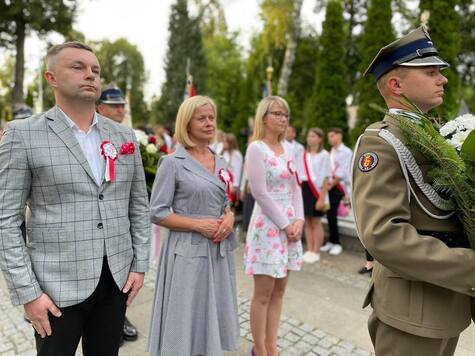 Posłanka Bożena Żelazowska w asyście dwóch osób składa wieniec