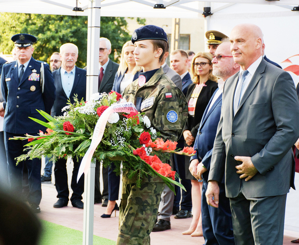 Wieniec od Sejmiku Województwa Mazowieckiego niesie harcerz w mundurze za nim idzie składający wieniec wiceprzewodniczący sejmiku Tomasz Kucharski