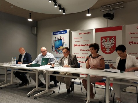 Pięć osób siedzi za stołem