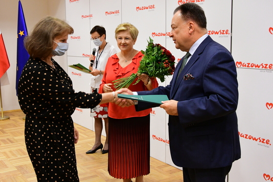 Marszałek wręcza teczkę z dokumentami kobiecie