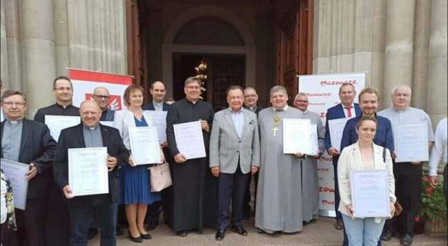 Grupa osób pozuje przed wejściem do budynku