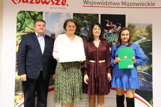 Zdjęcie pamiątkowe. Grupa osób na tle ścianki Mazowsze Serce Polski.