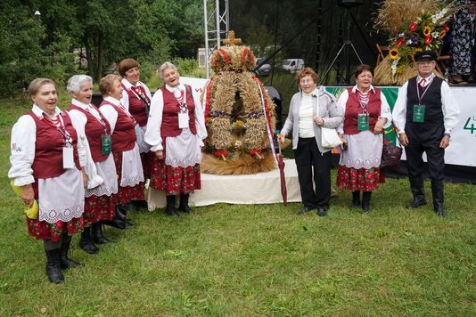 Kobiety w ludowych strojach stoją obok wieńca