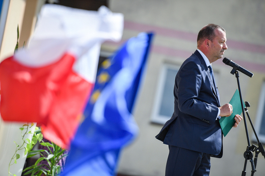 Elegancko ubrany mężczyzna przemawia na tle flag