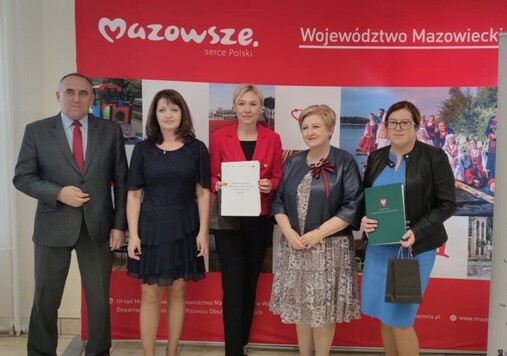 Zdjęcie pamiątkowe. Grupa osób na tle ścianki Mazowsze Serce Polski.