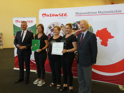 pięć osób, w tym trzy kobiety i dwóch mężczyzn stoi obok siebie. Kobiety trzymają w ręku umowy 
