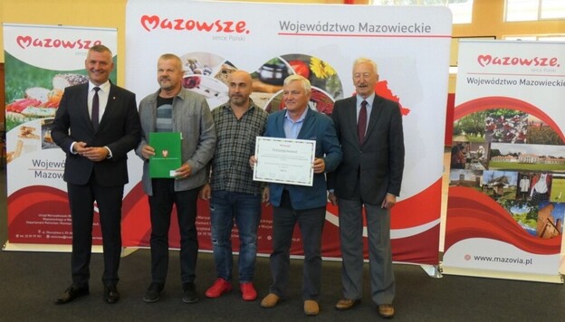 pięciu mężczyzn stoi przed banerem promującym województwo mazowieckie
