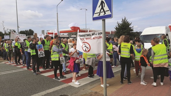 Protestujący ludzie z transparentami stoją na przejściu dla pieszych