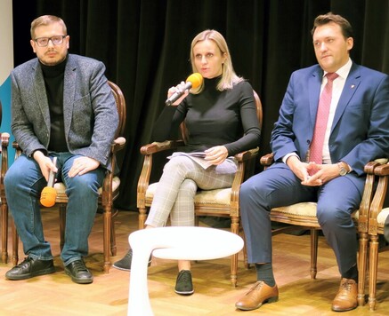 Radna mówi do mikrofonu, siedzi na scenie na fotelu. Po obu stronach na fotelach siedzą radni.