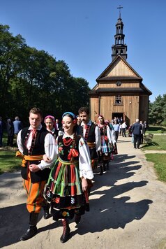 Artyści z zespołu Mazovia w strojach ludowych idą w kondukcie z kościoła