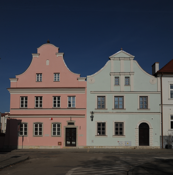 Dwie kamienice z ozdobnymi zwieńczeniami dachów. Widok od strony ulicy.