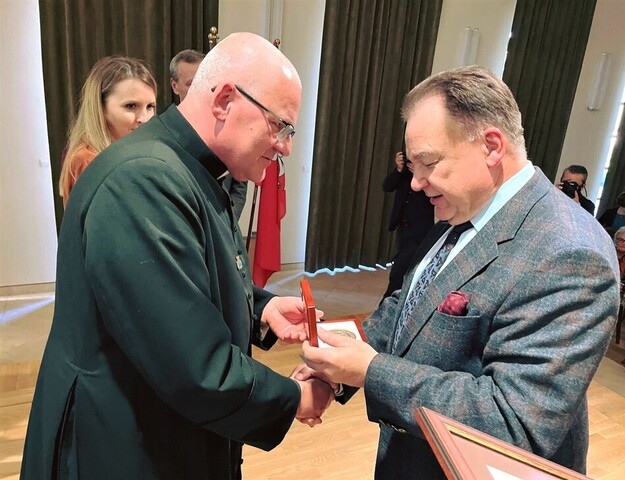 Marszałek wręcza dyrektorowi muzeum medal w etui. Obaj stoją naprzeciw siebie, bokiem do kamery, uśmiechają się