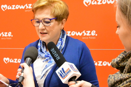 KObiueta przemawia do trzymanych przez dziennikarzy mikrofonów