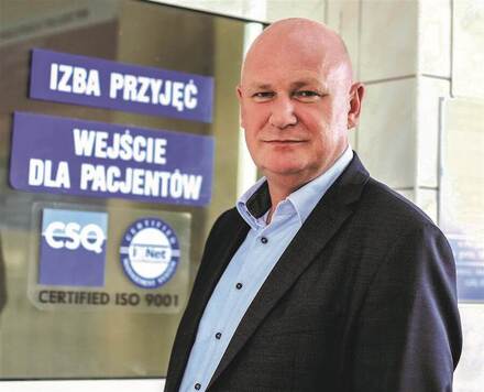 Mężczyzna w garniturze stojący przy drzwiach szpitala 