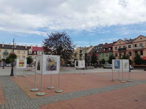 rynek miejski, na pierwszym planie widać plac wyłożony kostką brukową, wokół widoczna jest zabudowa mieszkalna 