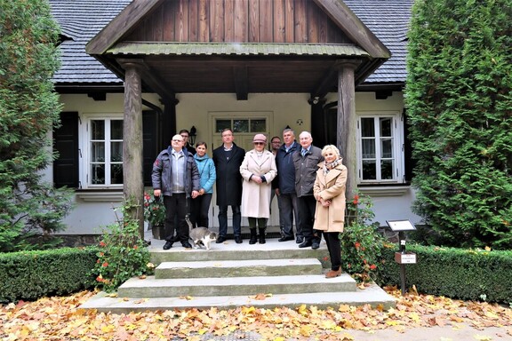 Grupa radnych stoi na schodach dworku w skansenie