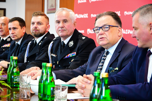 Marszałek oraz dwóch strażaków siedzą za stołem konferencyjnym