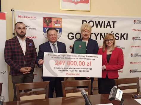 2556Dwóch mężczyzn i dwie kobiety pozują na ściance z czekiem