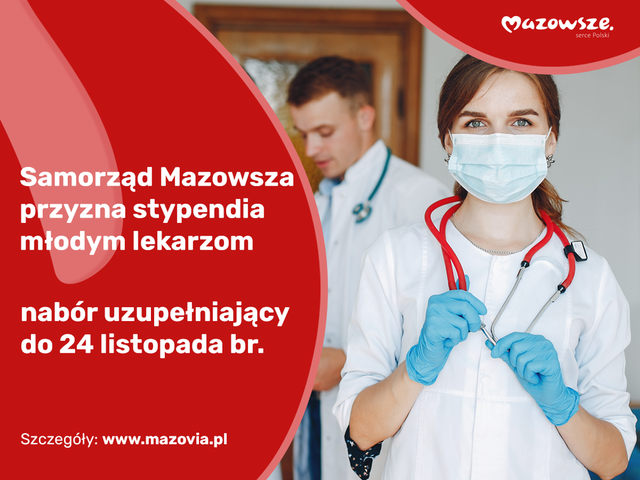 Młoda dziewczyna w lekarskim fartuchu, słuchawkami na szyi i maseczką na twarzy patrzy się prosto w kamerę. Z tyłu widać innych młodych lekarzy