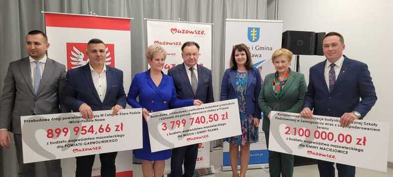 Marszałek, członkinie zarządu oraz beneficjenci pozują do zdjęcia z trzema czekami