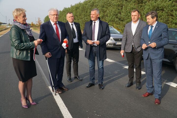 Wicemarszałek oraz przedstawiciele gminy i powiatu stoją na nowej, pustej drodze. Burmistrz Zwolenia coś mówi, pozostali słuchają go