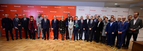 partnerzy umowy stoją na tle ściany z napisem Mazowsze