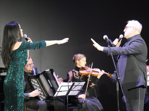 Magdalena Tunkiewicz-Zakrzewska i Wojciech Bardowski śpiewają i wyciągają do siebie ręce w geście pożegnania. W tle zespól muzyczny