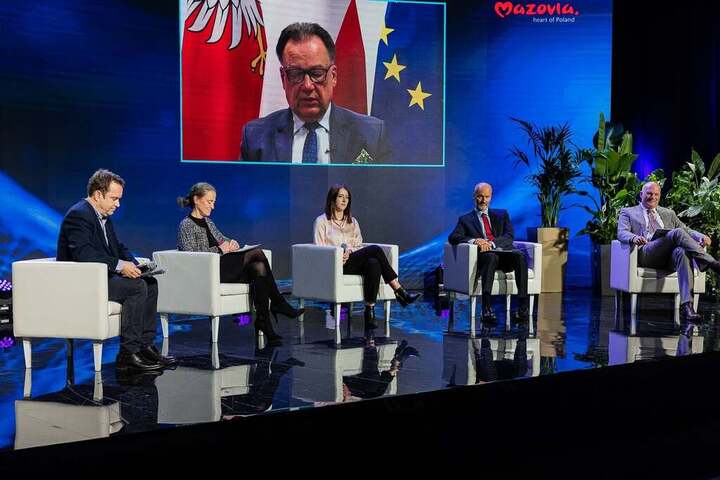 Na scenie na fotelach ustawionych obok siebie siedzą dwie kobiety i jeden mężczyzna. Za nimi na wielkim ekranie wyświetla się marszałek Adam Struzik