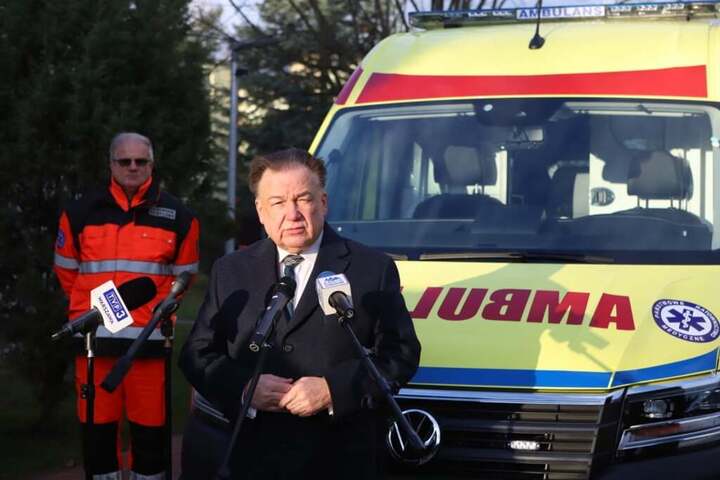 Marszałek Adam Struzik w trakcie przemówienia, w tle ambulans