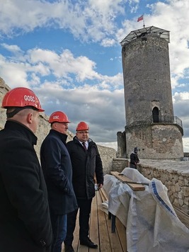 Wicemarszałek i dwaj mężczyżni zwiedzają zamek. W oddali widać wieżę zamku