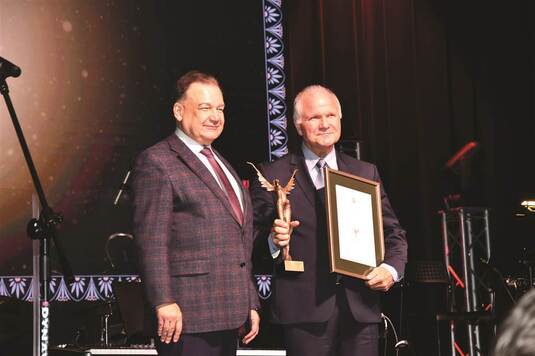 Dyrektor Muzeum Ziemi Mińskiej pozuje do pamiątkowego zdjęcia z marszałkiem Adamem Struzikiem. Dyrektor trzyma statuetkę i dyplom.