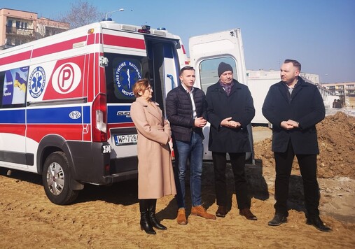 Trzech mężczyzn i kobieta stoją na tle karetki